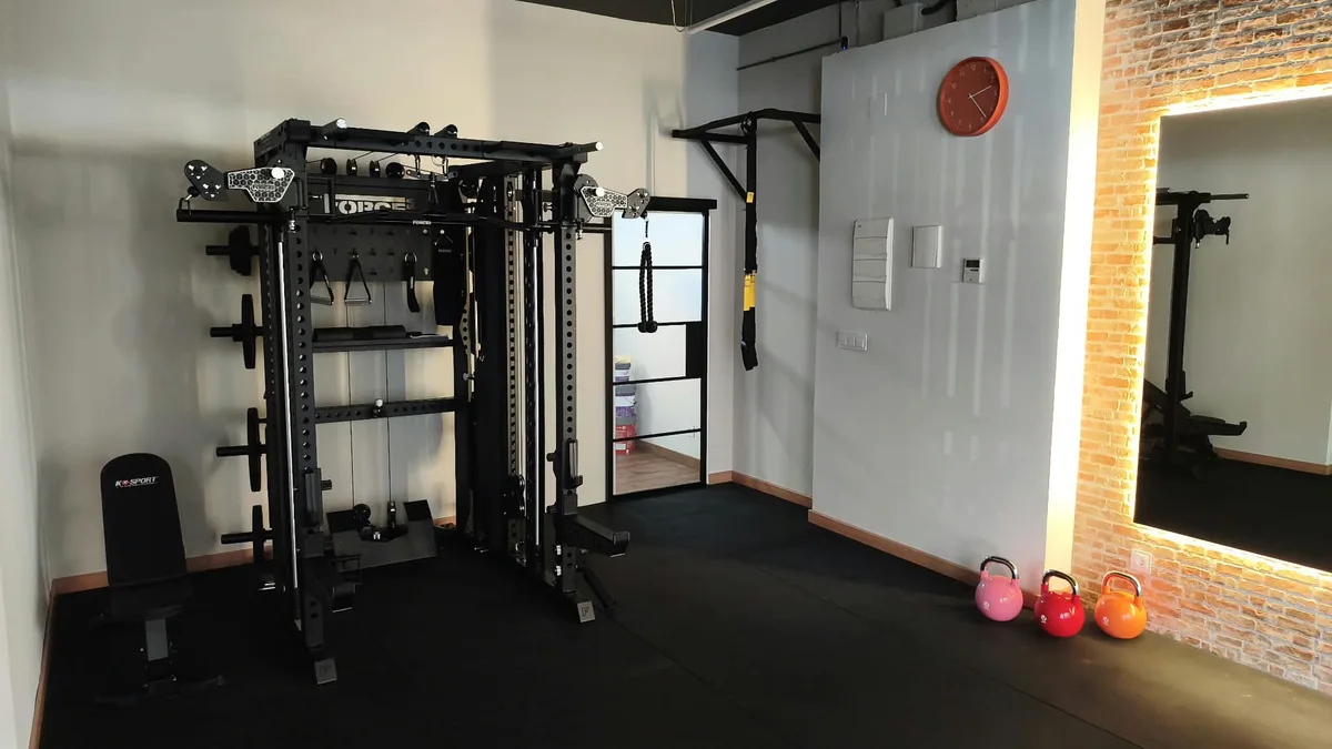Otra vista de la sala: zona de fuerza, material de entrenamiento y espejo de pared